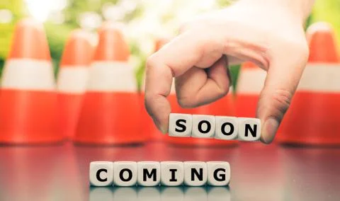 Dice form the expression "coming soon" in front of pylons. Stock Photos