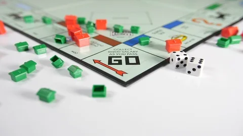 Dice thrown on to a board game of red and green house shape playing pieces Stock Footage 89193792
