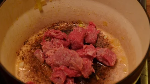 Diced beef being added to a casserole dish Stock Footage 121449312