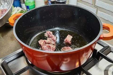 Diced beef meat is cooked in pot on gas stove Stock Photos