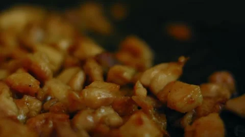 Diced chicken sizzling inside a black frying pan, 4K Stock Footage 341121809