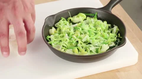 Diced fish being added to a spinach and leek medley Stock Footage 24671529