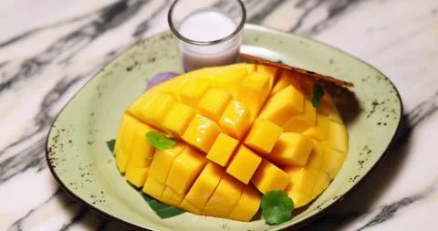 Diced mango served on plate with coconut milk, garnished with crispy Stock Footage 318117460