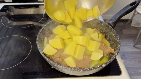 Diced potatoes added to simmering meat and vegetables in pan on stove 스톡 동영상 344631210