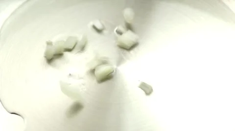 Diced raw onion pieces dropping onto fry pan of hot oil and stirred with with Stock Footage 68780560