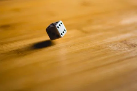 Dices bouncing on a wooden table. Single or group Stock Photos