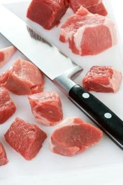 Dicing raw lamb with a kitchen knife Stock Photos