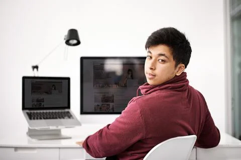 Did someone call for a tech guru. Portrait of a young man sitting at his Stock Photos