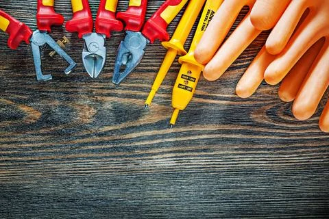 Dielectric gloves Electrical tester Wire stripper Cutting pliers on wooden board Stock Photos