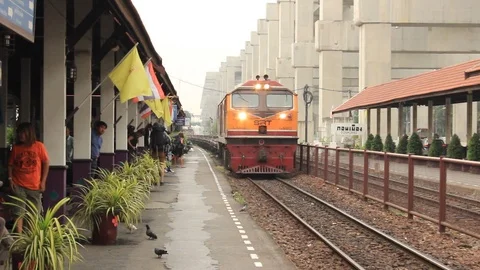 Diesel train pulling a long trail of flatcars past the platforms of a station Stock Footage 100750291