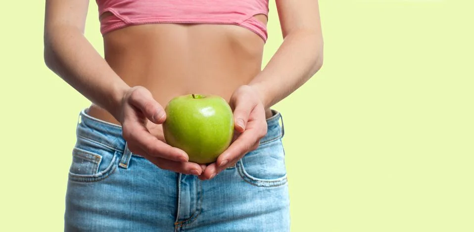 Diet concept. Beautiful perfect woman with slim waist is holding apple on fad Stock Photos