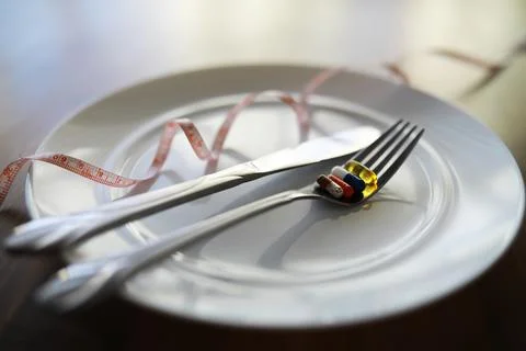 Diet Concept with Pills and Measuring Tape on Empty Plate Stock Photos