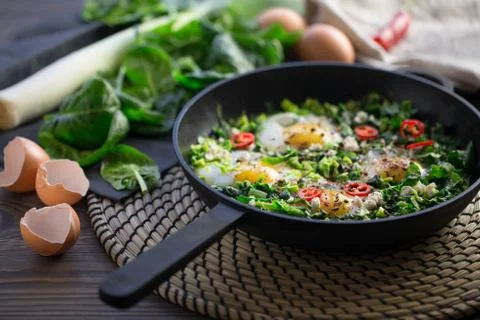 Diet green spinach shakshuka served on a wooden rustic style table. Stock Photos
