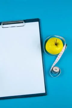 The diet plan. White sheet on the tablet and apples with measuring tape on a  Stock Photos