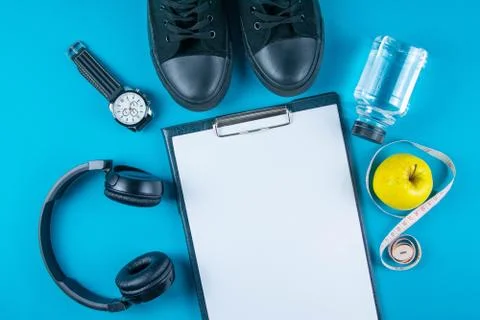 The diet plan. White sheet on the tablet among the black sneakers, headphones Stock Photos