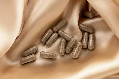 Dietary supplement multivitamin complex capsules on silk background 库存照片