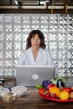 Dietitian working on laptop at table with assorted nutrient products Stock Photos
