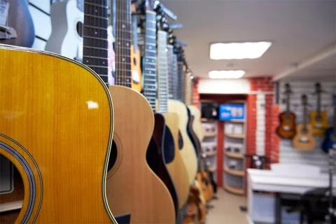 Different acoustic six-string guitars in a music store Stock Photos