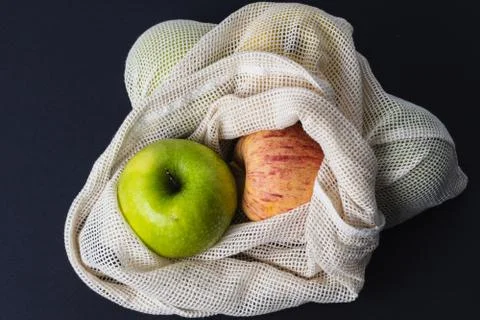 Different apples in string bag, shopper on the black background, zero waste c Stock Photos