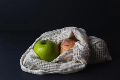 Different apples in string bag, shopper on the black background Stock Photos