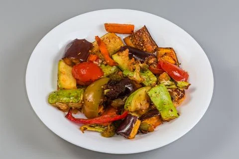 Different baked vegetables on dish on a gray background Stock Photos