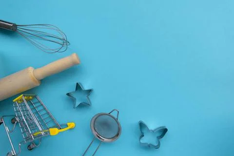 Different baking tools with shopping grocery cart on blue background, top view Foto stock