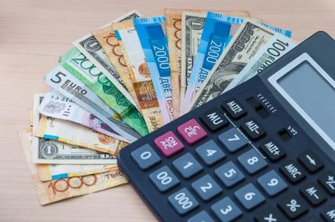 Different banknotes of different denominations are stacked in a fan and a cal Stock Photos