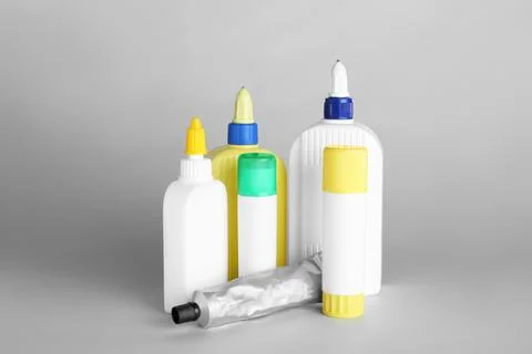 Different bottles of glue on grey background Stock Photos