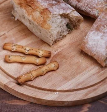 Different bread on a round cutting board on a wooden table Stock Photos