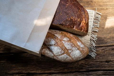 Different bread rye and baguette in bag isolated on wood Stock Photos