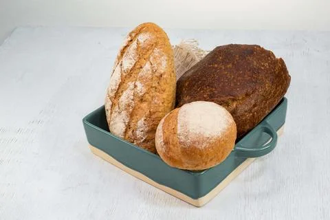 Different bread rye round baguette isolated in blue tray on white wood Stock Photos