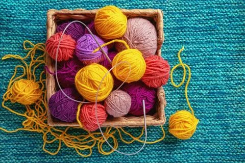 Different bright balls of wool and knitting needles on knitted background Stock Photos