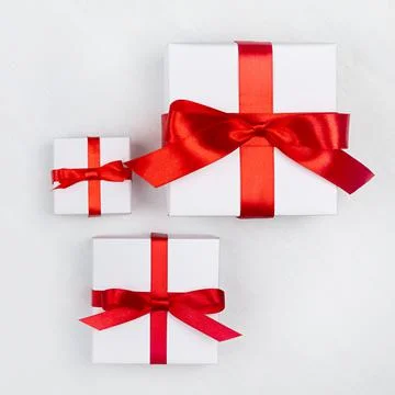 Different bright simple white gift box with red silk ribbon on white wooden t Stock Photos