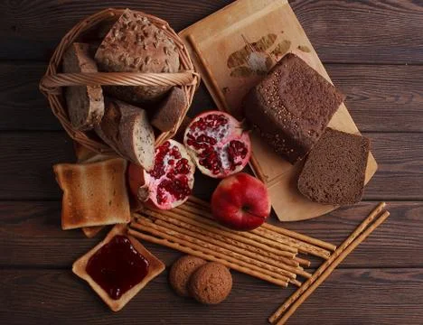 Different buns of fresh bread and spikelets of wheat on a brown vintage backg Stock Photos