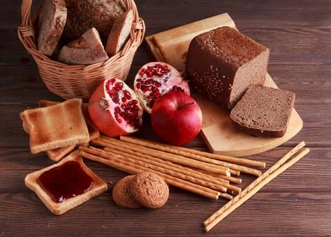 Different buns of fresh bread and spikelets of wheat on a brown vintage backg Stock Photos