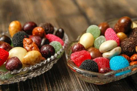 Different candy in a crystal bowl on old wooden table Stock Photos
