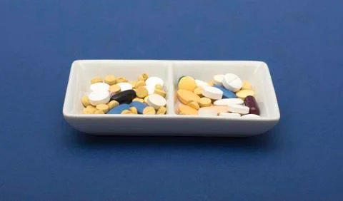 Different Capsule and tablets in plate on blue background Stock Photos