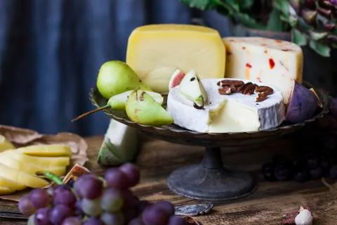 The different cheese on metal tray, fresh fruits on the wooden background Stock Photos
