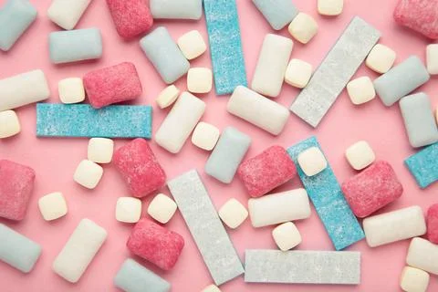 Different chewing gums on pink background. Stock Photos