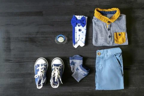 Different child clothes, pants, shirt, accessories on black wooden table wi.. Foto stock