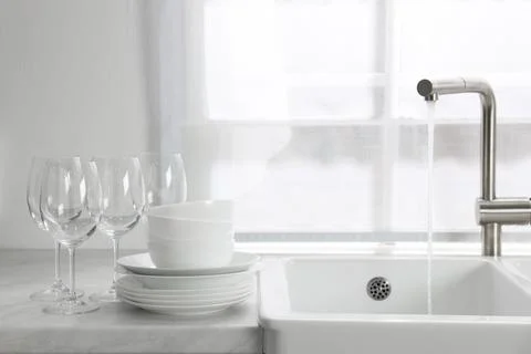 Different clean dishware and glasses on countertop near sink in kitchen Stockfoto's