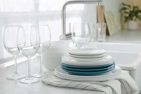 Different clean dishware and glasses on countertop near sink in kitchen Stockfoto's