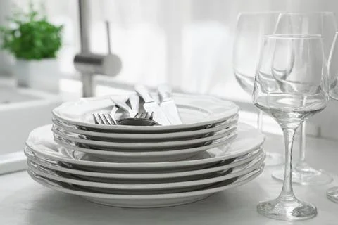 Different clean dishware, cutlery and glasses on countertop in kitchen, close Stockfoto's
