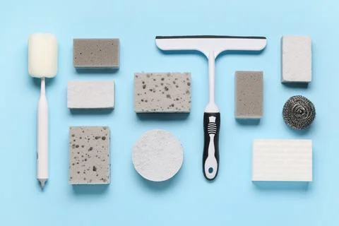 Different cleaning sponges with scraper on blue background Stock Photos