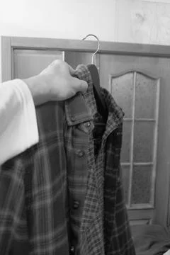 Different clothes in a persons hand on a hanger, shirts of different styles and Stock Photos