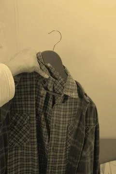 Different clothes in a persons hand on a hanger, shirts of different styles and Stock Photos