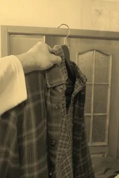 Different clothes in a persons hand on a hanger, shirts of different styles and Stock Photos