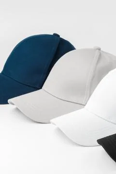 Different colored baseball caps on a white surface for display or sale Stock Photos