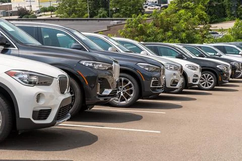 Different colored BMW SUVs lined up downhill at a dealership Stock Photos
