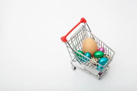 Different colored chicken eggs are in the grocery cart on the white backgroun Stock Photos